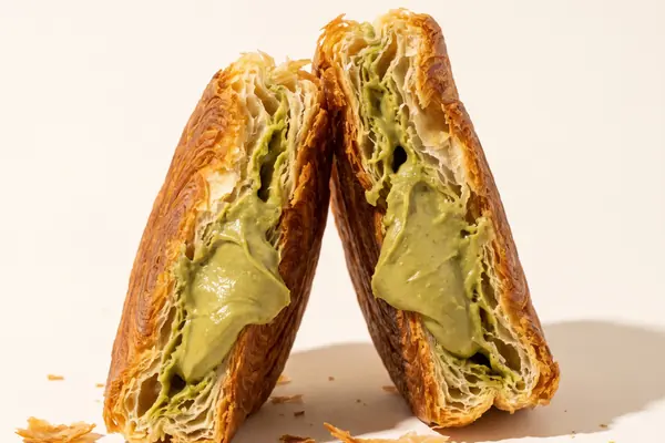 Aufgebrochener New York Roll, die Blätterteigschichten und die Pistaziencreme im Inneren sind zu sehen