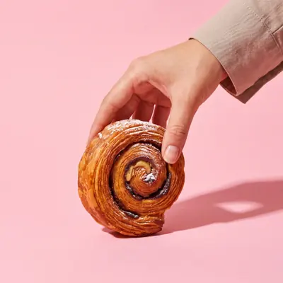 Eine Hand nimmt einen New York Roll vom Tisch